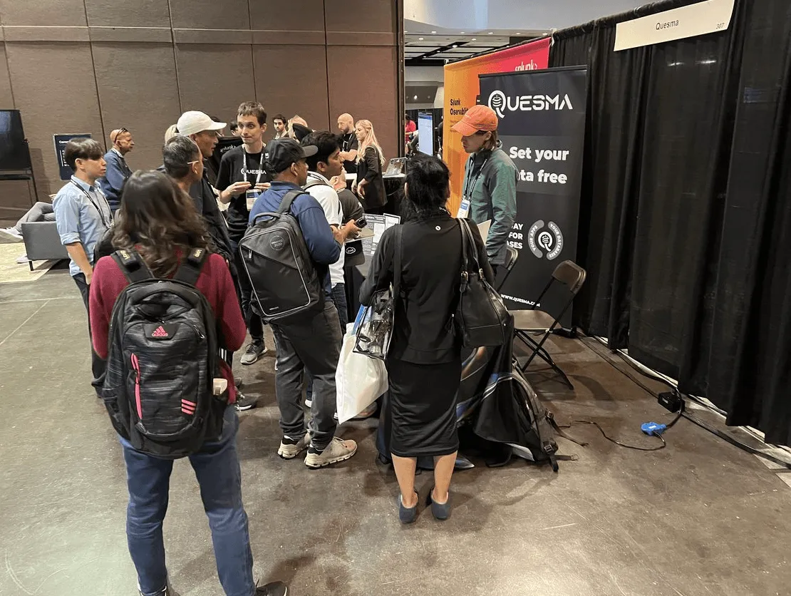 Group of attendees gathered at the Quesma booth during a tech conference.